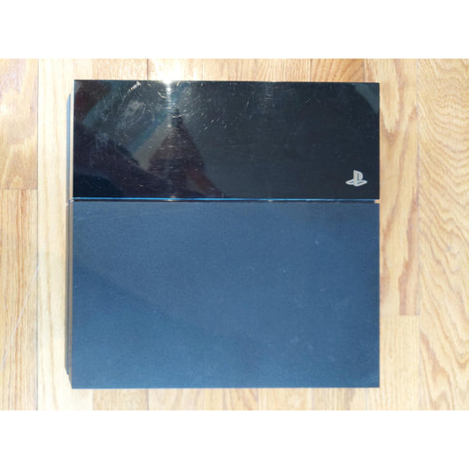 PlayStation 4 gaming console with controller and cables on a wooden surface