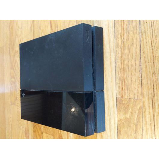 PlayStation 4 gaming console with controller and cables on a wooden surface