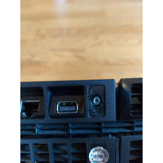 PlayStation 4 gaming console with controller and cables on a wooden surface