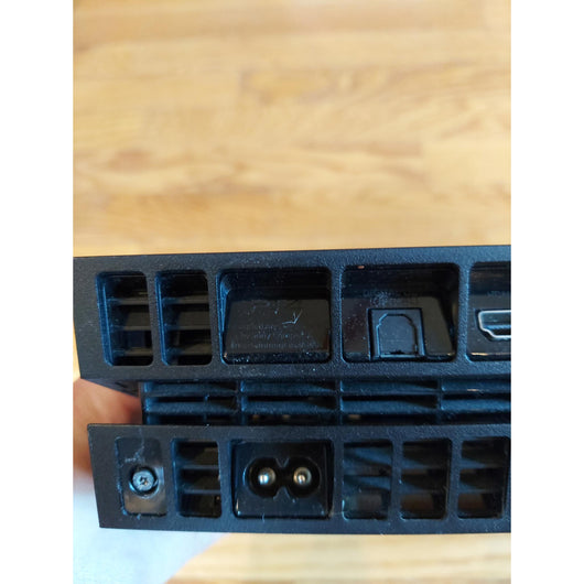 PlayStation 4 gaming console with controller and cables on a wooden surface