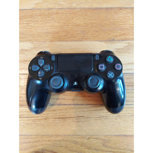 PlayStation 4 gaming console with controller and cables on a wooden surface