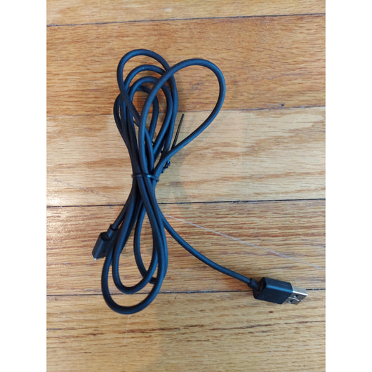PlayStation 4 gaming console with controller and cables on a wooden surface